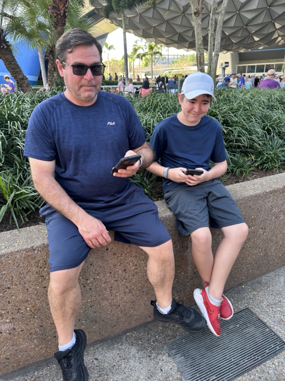 Teenager and parent checking the My Disney Experience app while visiting EPCOT at Walt Disney World.