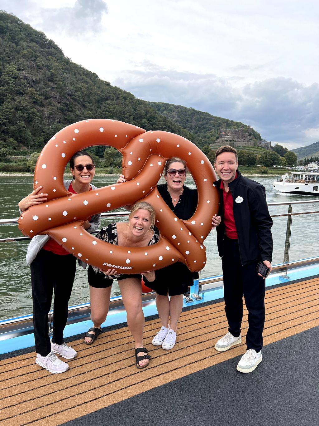 Travellers and an Adventure Guide pose with an oversized pretzel float on the deck of a river cruise ship.