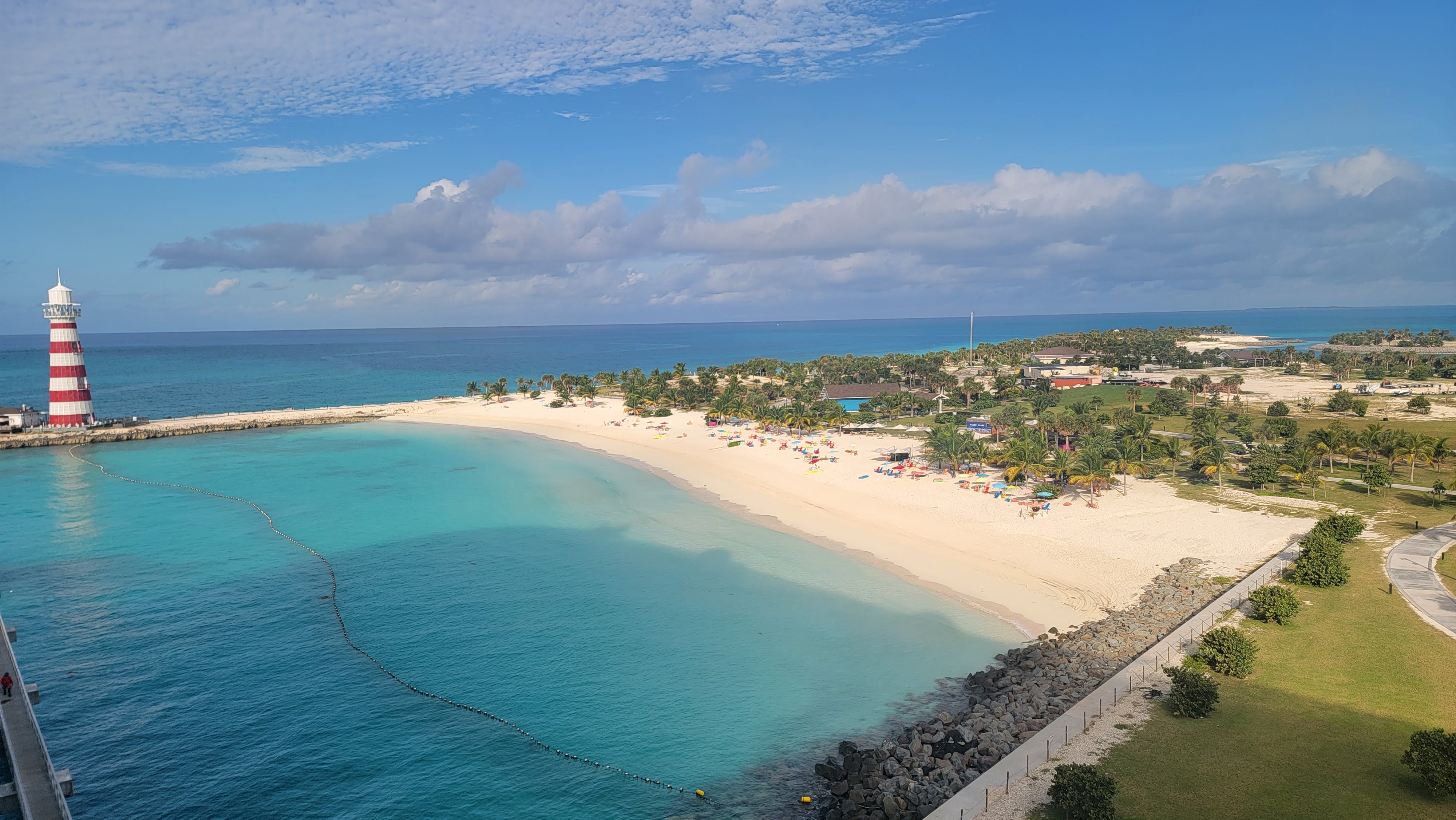 Aerial view of Ocean Cay MSC Marine Reserve with a red and white lighthouse, sandy beach and turquoise water.