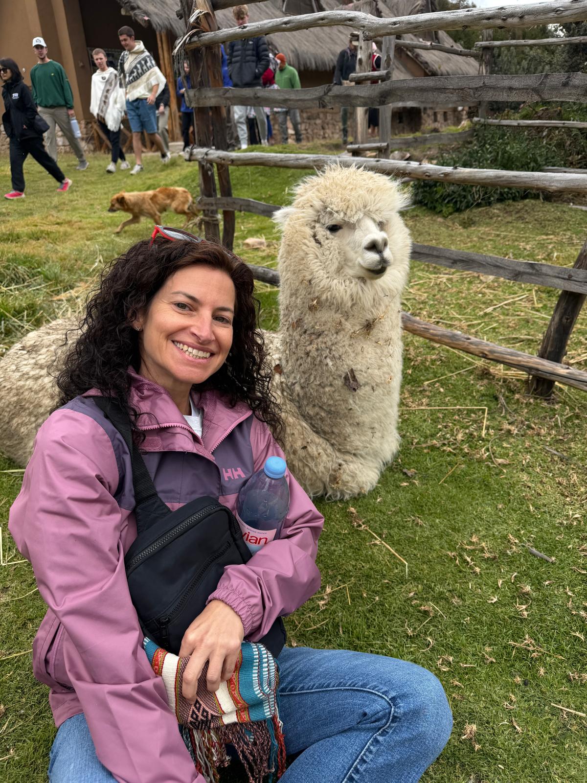 Marie kneeling beside a white alpaca at Potato Park in Peru’s Sacred Valley.